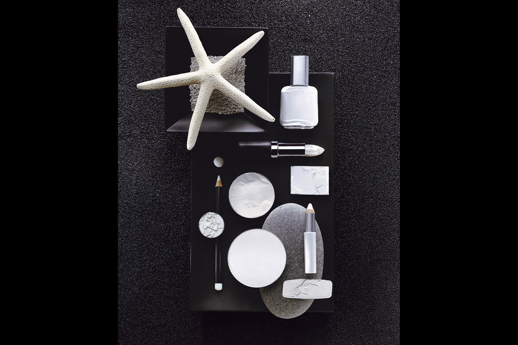 Cosmetics Still Life, White Makeup on Black Sand